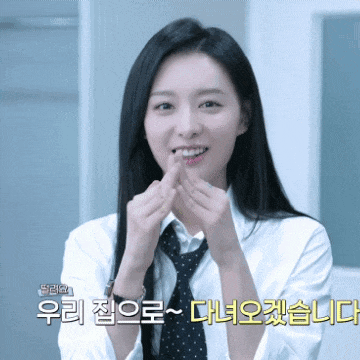 a woman wearing a white shirt and tie is smiling and making a heart shape with her fingers