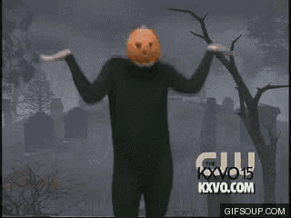 a man with a pumpkin head is dancing in front of a cemetery
