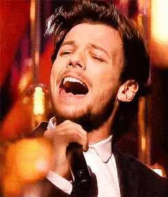 a man is singing into a microphone with his mouth open .