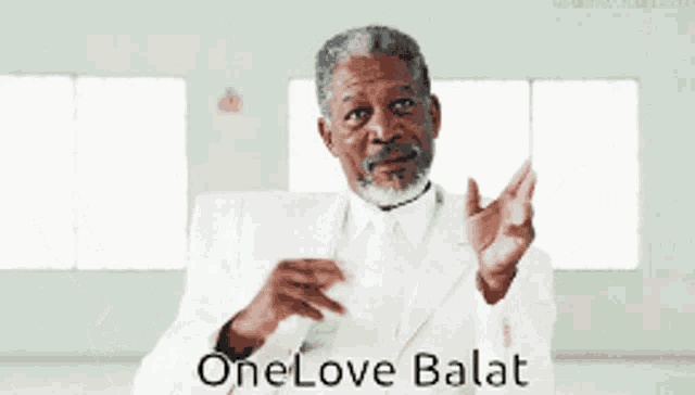 a man in a white suit and tie says one love balat