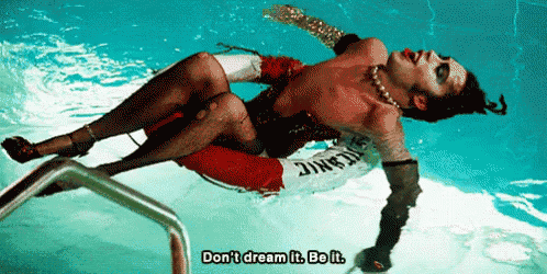 a man is laying in a swimming pool with the words " don 't dream it be it " written below him