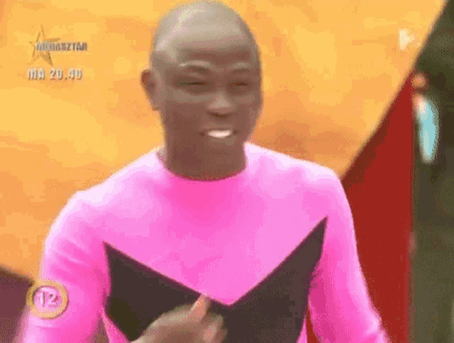 a man in a pink and black costume is standing in front of a yellow wall .