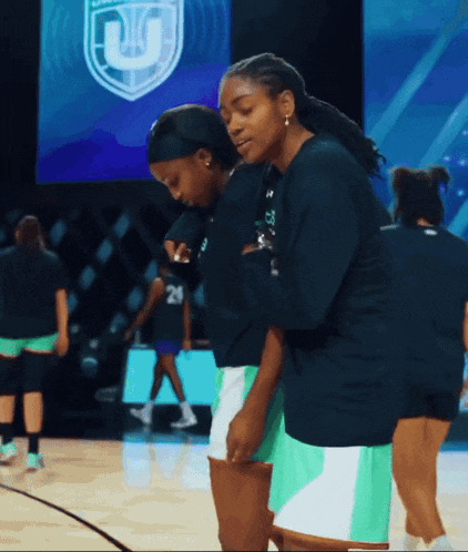a group of female basketball players are standing on a court with the letter u behind them