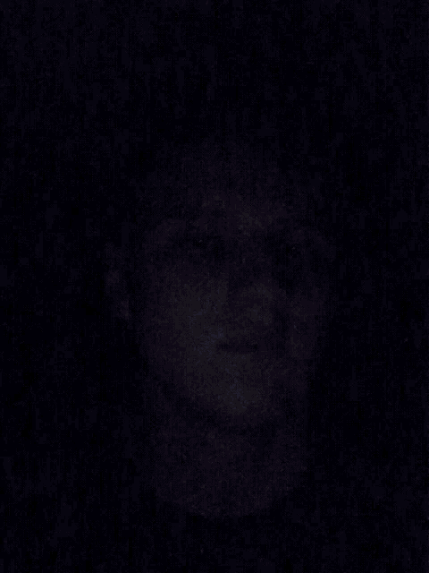a close up of a young man 's face in a dark room