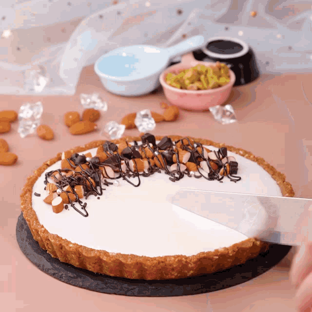 a person is cutting a pie with nuts on it