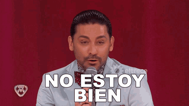 a man in a suit and bow tie holds a microphone and says " no estoy bien "