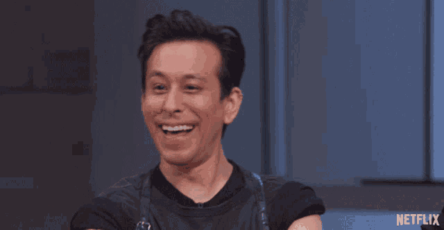 a man in a black shirt is laughing with a netflix logo behind him