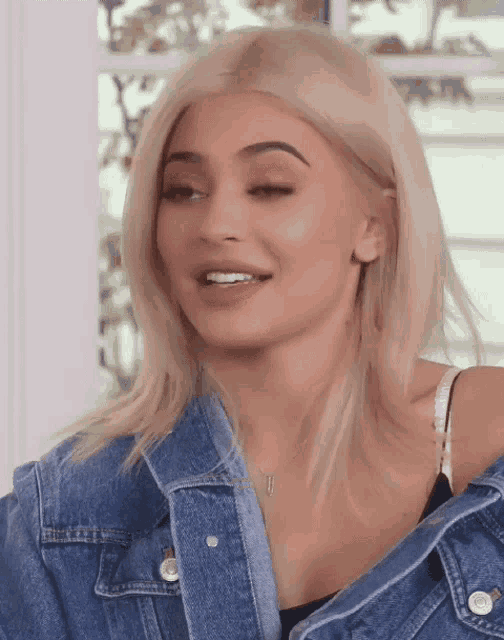 a woman with blonde hair is wearing a denim jacket and bra