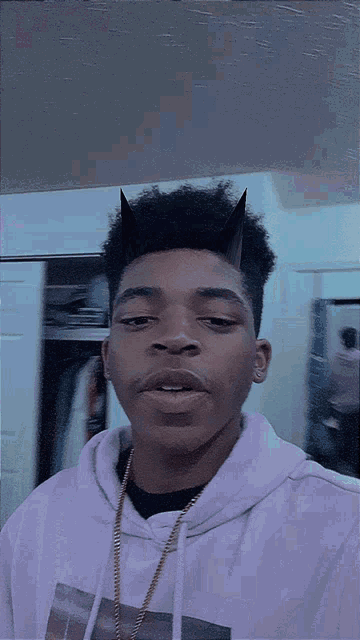 a young man with horns on his head is wearing a white hoodie