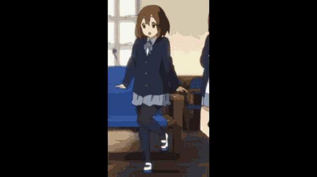 a girl in a school uniform is standing on one leg in front of a blue couch