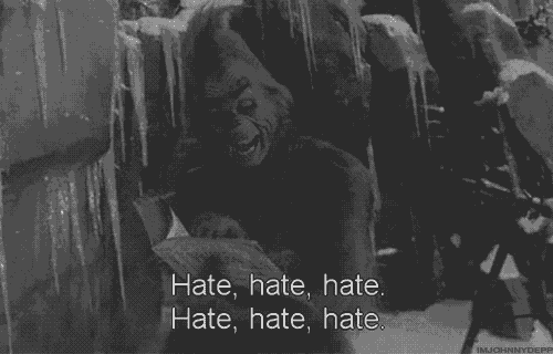 a grinch is holding a piece of paper and saying hate hate hate