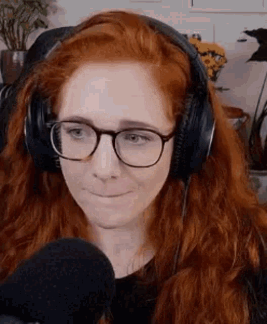 a woman with red hair is wearing headphones and glasses .
