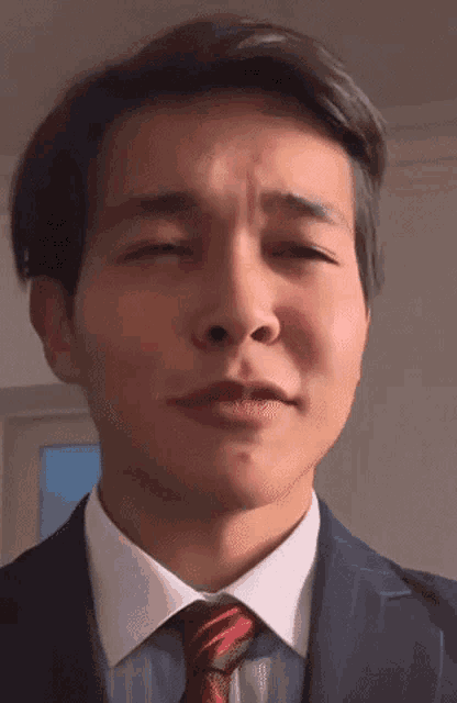 a man in a suit and tie is making a funny face with his eyes closed