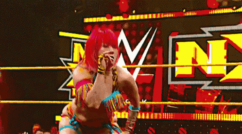 a woman with red hair is standing in a wrestling ring with a yellow rope around her waist .