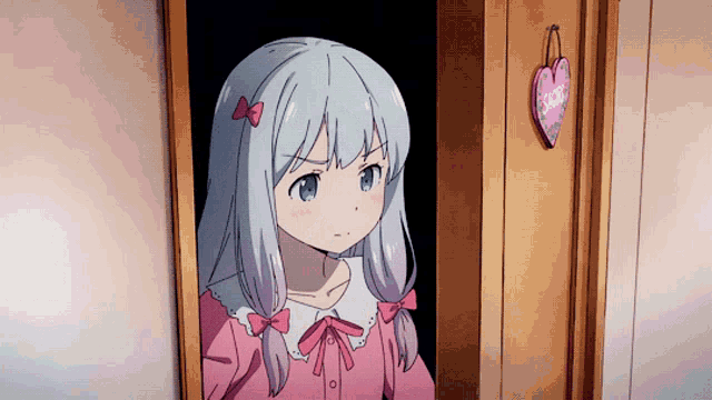 a girl in a pink dress stands in a doorway with a heart hanging on the wall behind her