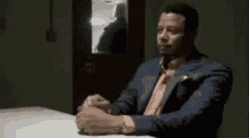 a man in a prison uniform is sitting at a table with another man .