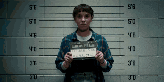 a woman is holding a mugshot that says lenora hills r.d.