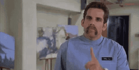 a man with a mustache is standing in front of a painting in a room .