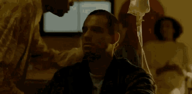 a man kissing another man on the forehead in a hospital room .