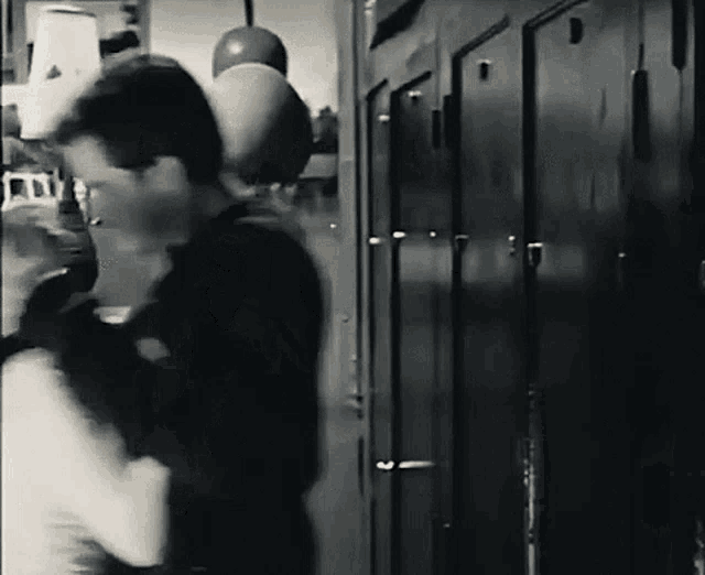 a black and white photo of a man standing in a locker room .