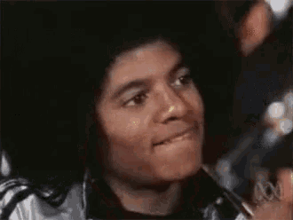 a close up of a man 's face making a funny face while wearing a silver jacket .