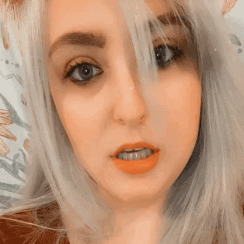 a close up of a woman 's face with orange lipstick