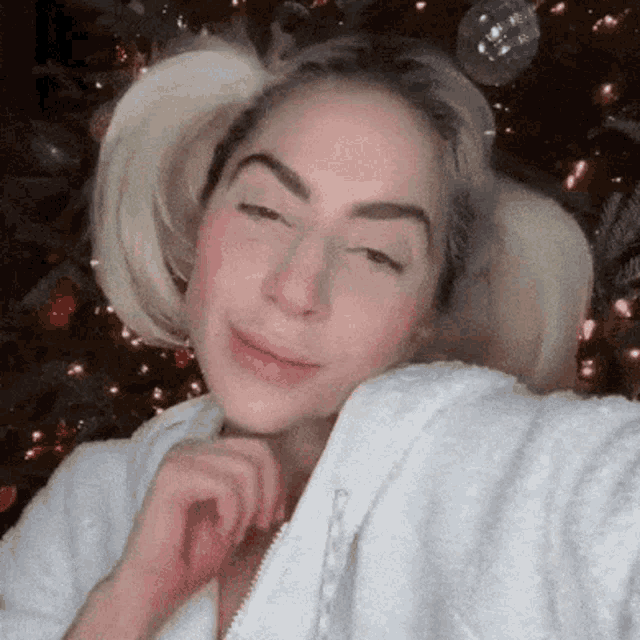 a woman taking a selfie with a christmas tree in the background