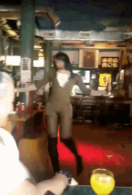 a woman dancing in a restaurant with a glass of orange juice on the table