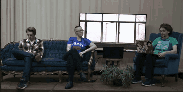 a man wearing a blue shirt that says local is sitting on a blue couch