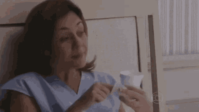 a woman is sitting in a hospital bed holding a cup and a napkin .