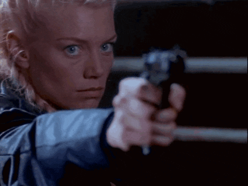 a close up of a woman 's face while holding a gun