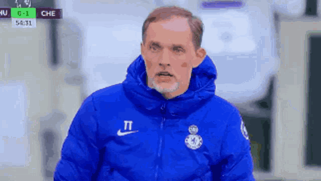 a man wearing a blue jacket with the letter t on the front