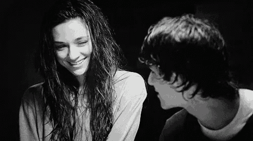 a black and white photo of a boy and a girl looking at each other .