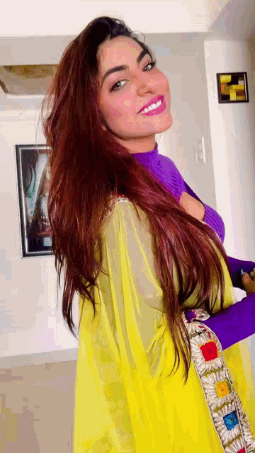 a woman with long red hair is wearing a yellow top and purple sweater