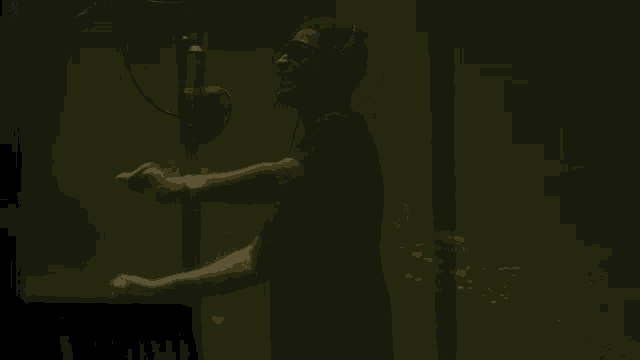a man is singing into a microphone with his arms outstretched