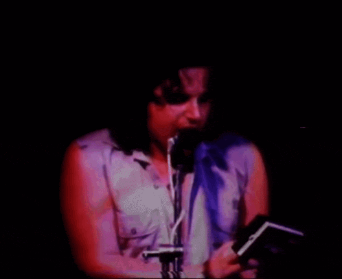 a man singing into a microphone while holding a book in his hand
