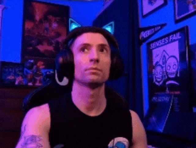 a man wearing headphones and a black tank top is sitting in a chair .