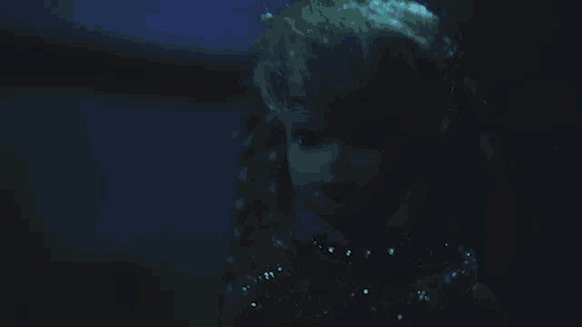 a doll is standing in a dark room with a dresser in the background