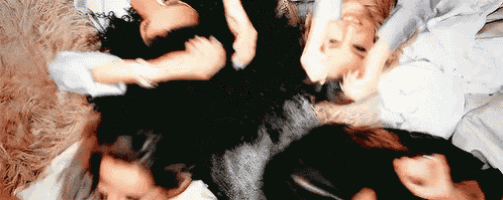 a group of women are laying in a circle on the floor with their heads together .