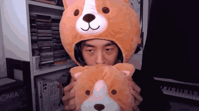 a man wearing a teddy bear hat holds a stuffed dog