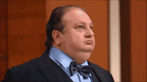 a man in a suit and bow tie is making a face .