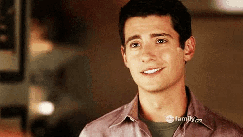 a man wearing a shirt that says abc family is smiling .