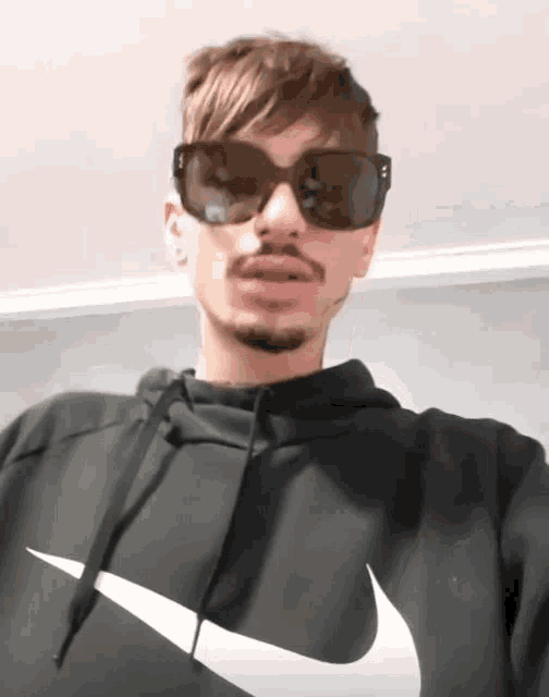 a man wearing sunglasses and a nike sweatshirt