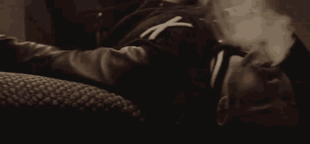 a man laying on a couch smoking a cigarette with the letter x on his chest