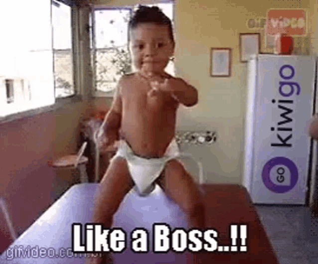 a baby in a diaper is standing on a table with the words like a boss written on it .