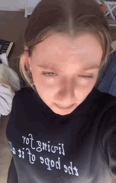 a girl wearing a black shirt that says " rot gnioij "