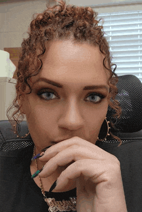 a woman with curly hair and blue eyes is wearing a necklace that says ' i love you ' on it