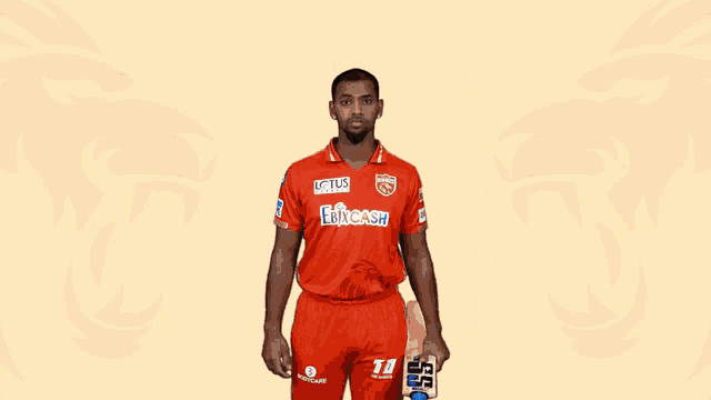 a man holding a cricket bat with lotus written on his shirt