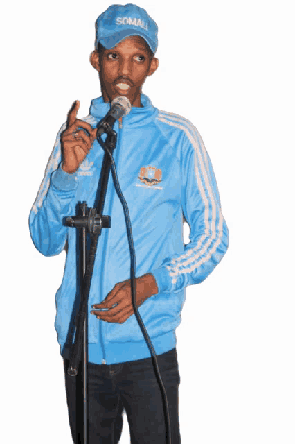 a man wearing a somalia hat and a blue adidas jacket is speaking into a microphone