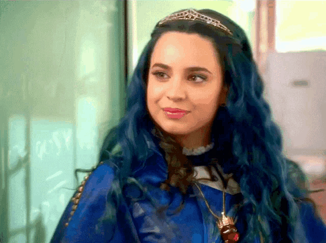 a woman with blue hair and a tiara on her head smiles